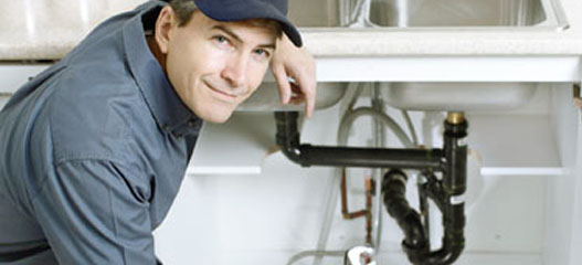 fontanero delante de un fregadero sonriendo a la cámara