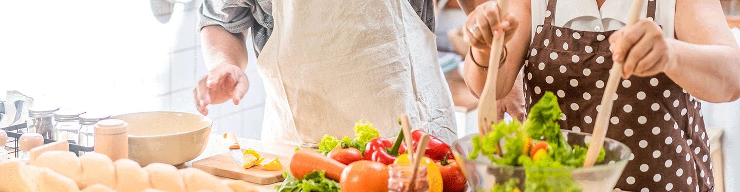 Dos personas haciendo la comida con una ensalada