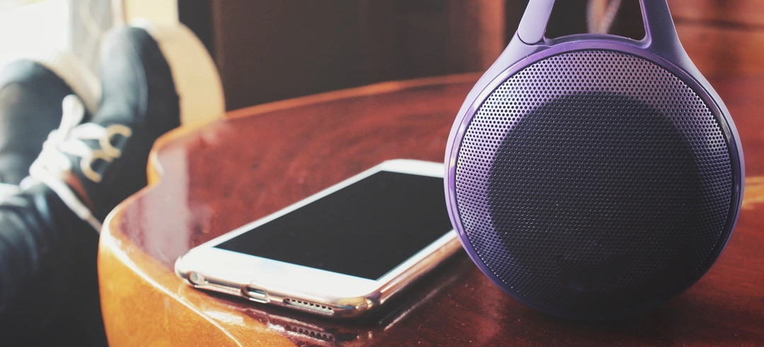 Smartphone junto a un altavoz apoyados en una mesa